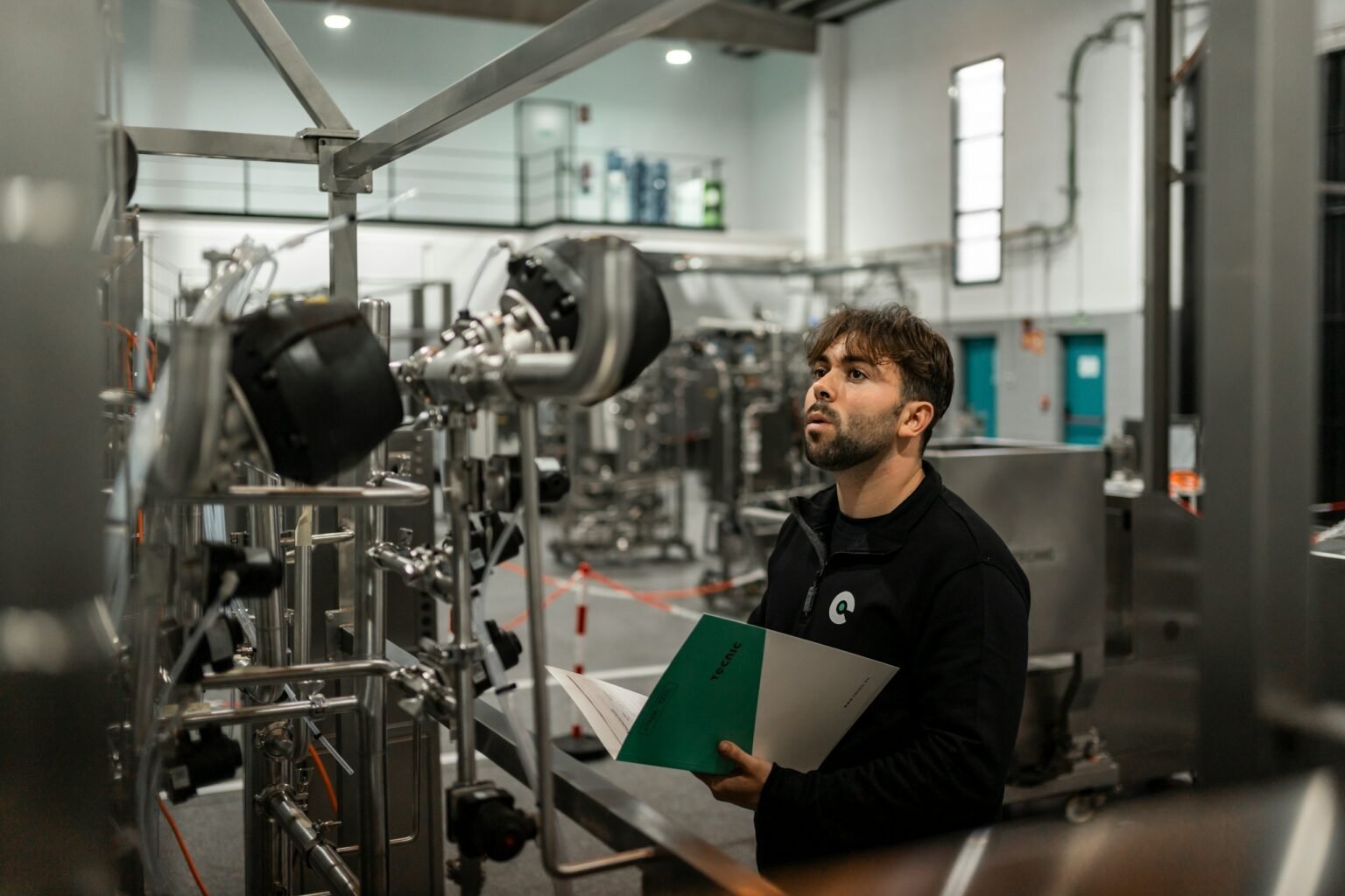 CleanBelt Technician reviewing the installation of an industrial piping system in a validation room, with technical documentation in hand.