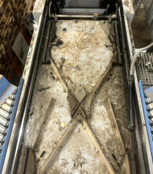 contaminated sorting conveyor diverter structure covered in heavy warehouse debris and operational dust.